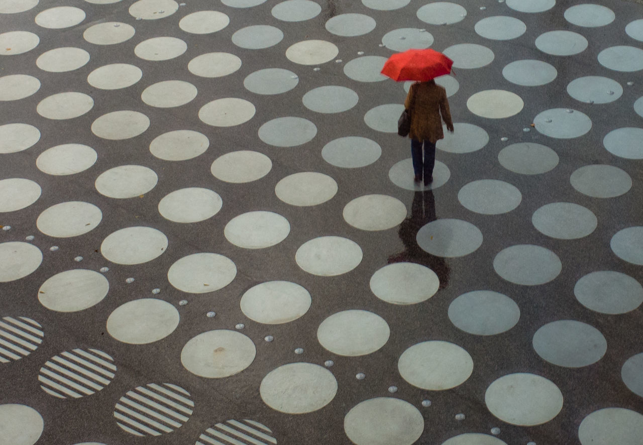 LOW SECTION OF WOMAN STANDING ON WET GLASS OF UMBRELLA