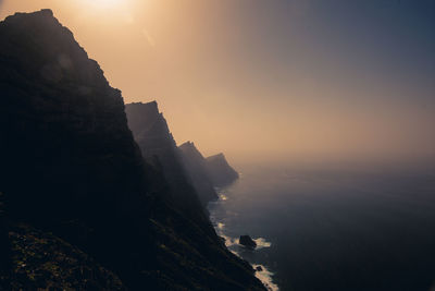 Scenic view of cliff against sky during sunset