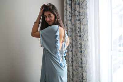 Girl try on and consider a tunic handmade dress with knitted fringe with tassels, blue color, 