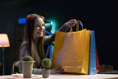 Portrait of young woman with shopping bags against black background
