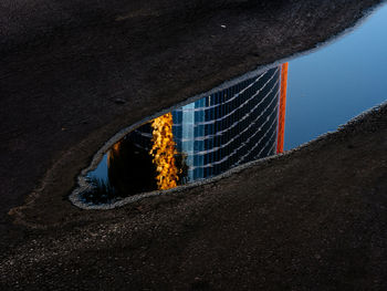 Reflection of a sunset on a building shimmering in a puddle