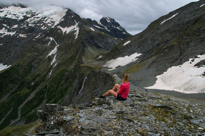 Rear view of woman on rock against mountains