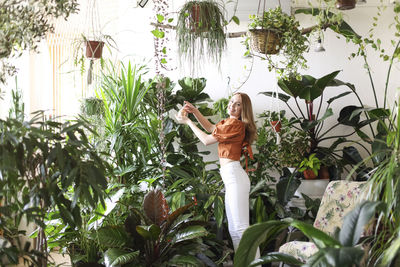 Young woman with potted plants against trees