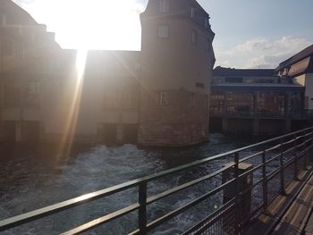 Buildings by river in city against sky