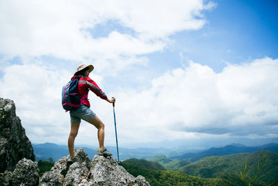 Rear view of man standing on mountain against sky