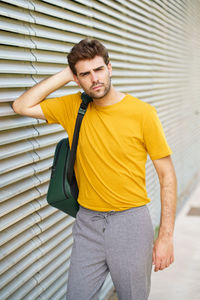 Portrait of young man standing against yellow wall