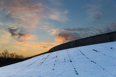 Scenic view of snow covered field against sky at sunset