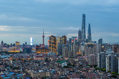 Aerial view of buildings in city against cloudy sky