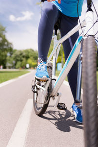 Low section of woman riding bicycle on road