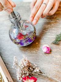 Close-up of hand holding pink flowers on table