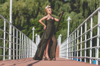 Full length portrait of woman standing on footbridge