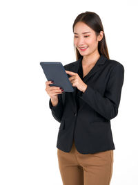 Smiling young woman using smart phone against white background