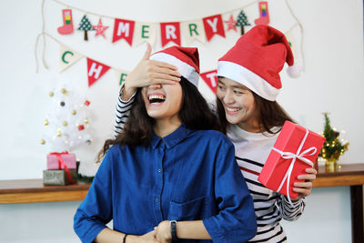 Smiling woman surprising friend during christmas