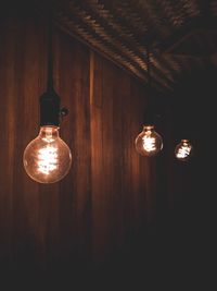 Low angle view of illuminated light bulbs hanging from ceiling