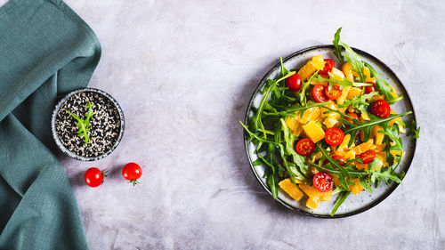 Dietary salad of orange slices, cherry tomatoes and arugula on a plate top view web banner