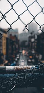 Close-up of chainlink fence by street in city