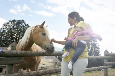 Woman with baby touching horse