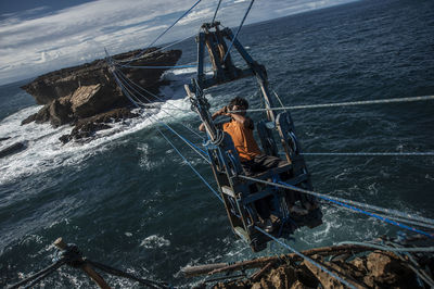 Man on overhead cable car over sea