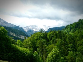 Scenic view of lush green mountains against cloudy sky