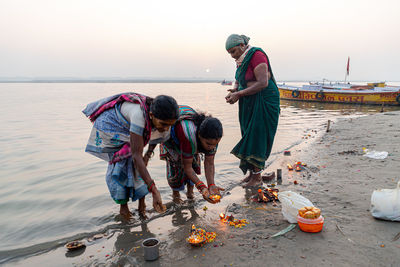 People on beach by sea against sky