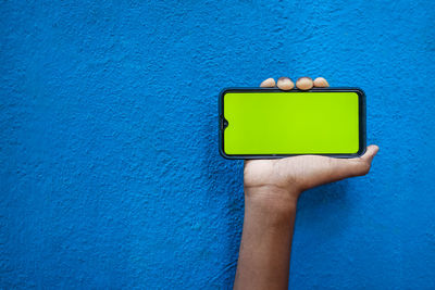 Close-up of human hand holding blue wall