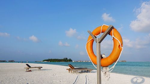 Deck chairs on beach against sky