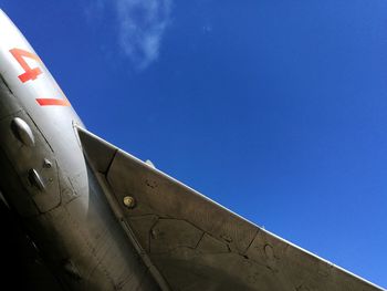 Low angle view of airplane wing against blue sky