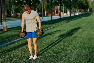 Full length of man holding ball while sitting on grass