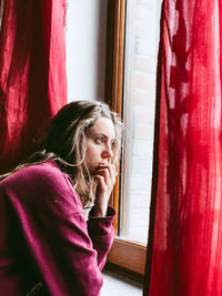 Young woman looking through window