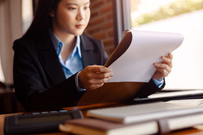 Businesswoman reading document sitting in office