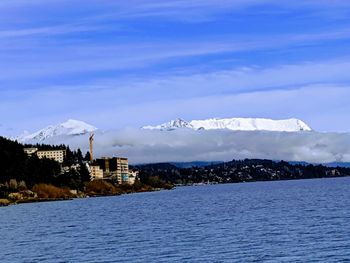 Scenic view of buildings by snowcapped mountains against sky