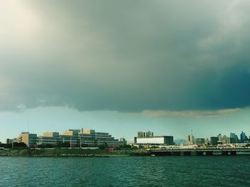 Sea by city against cloudy sky