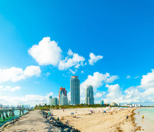 Panoramic view of beach and buildings against blue sky