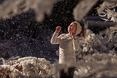 Girl in snowdrift enjoys snowflakes at night