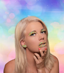 Close-up portrait of young woman against colored background