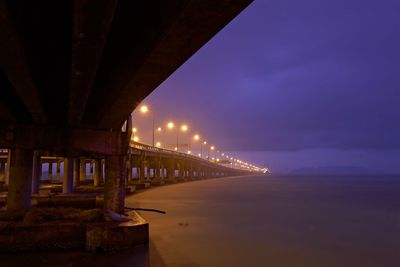 Illuminated bridge against sky at night