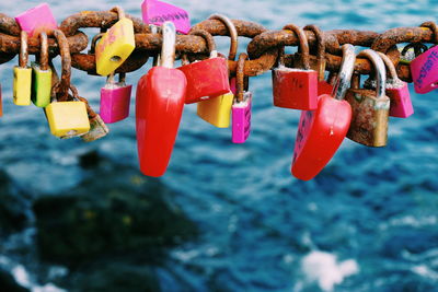 High angle view of love locks on rusty metallic chain over sea