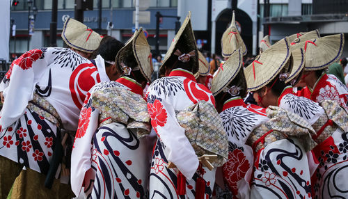 Rear view of people in traditional clothing standing outdoors