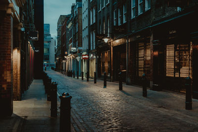 Empty footpath amidst buildings in city