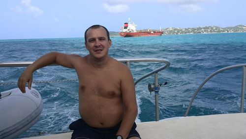 Portrait of shirtless man playing at beach against sky