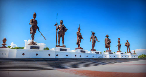 Low angle view of statues against blue sky