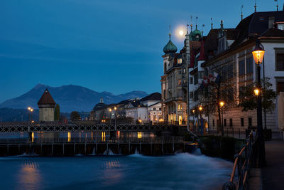 Illuminated buildings against blue sky at night