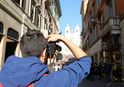Rear view of teenage boy photographing church in city