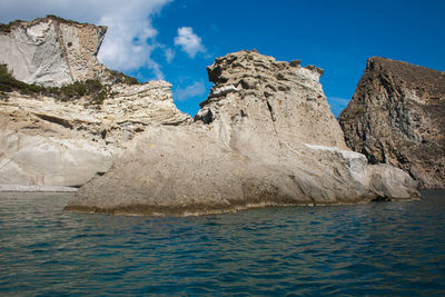 Rock formations by sea against blue sky