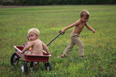 Side view of boy playing with dog on field