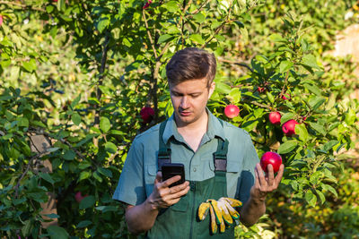 Portrait of young man holding fruits at farm