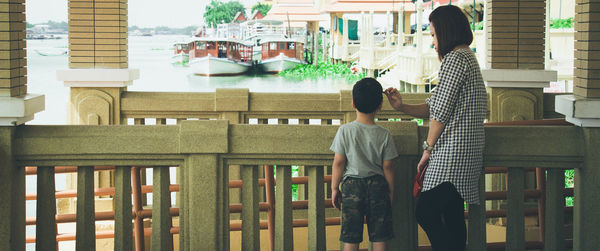 Rear view of people standing by railing