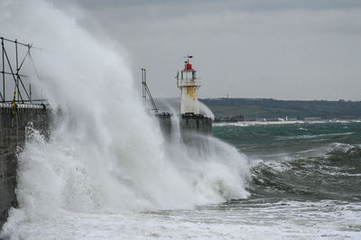 Waves splashing on shore against sky