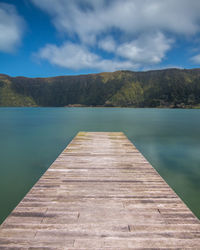 Pier amidst swimming pool by lake against sky