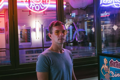 Portrait of young man against illuminated window at night